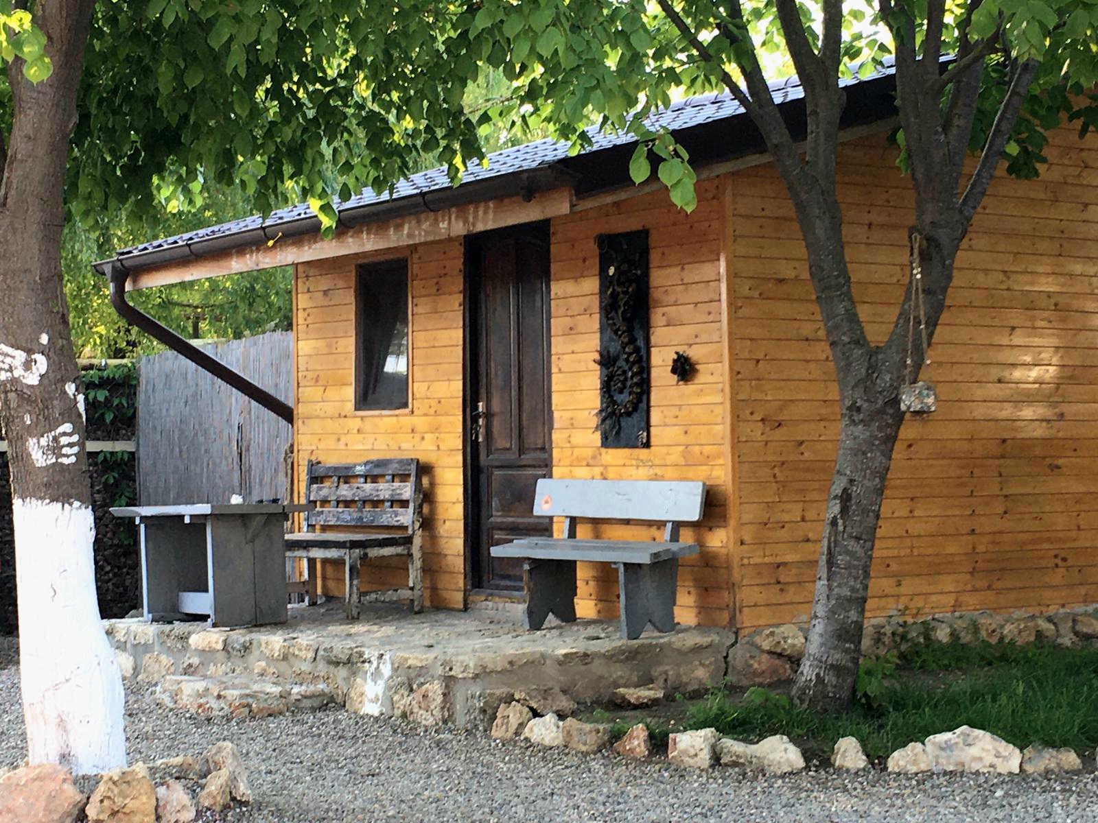 Magic Garden bungalow exterior with wooden facade and bench under trees