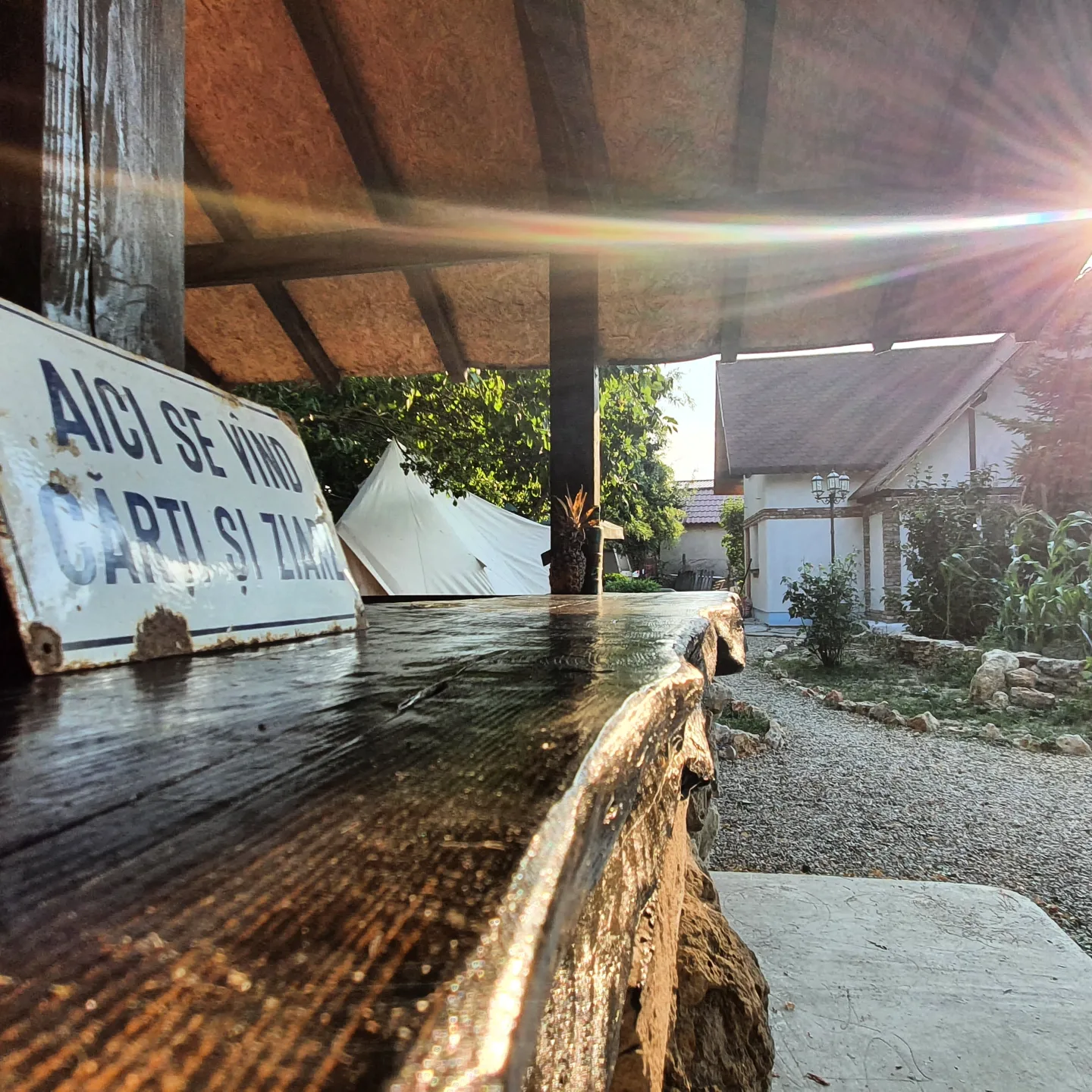 Golden sunbeams through the wooden terrace at Magic Garden, Vama Veche — tipis in garden background