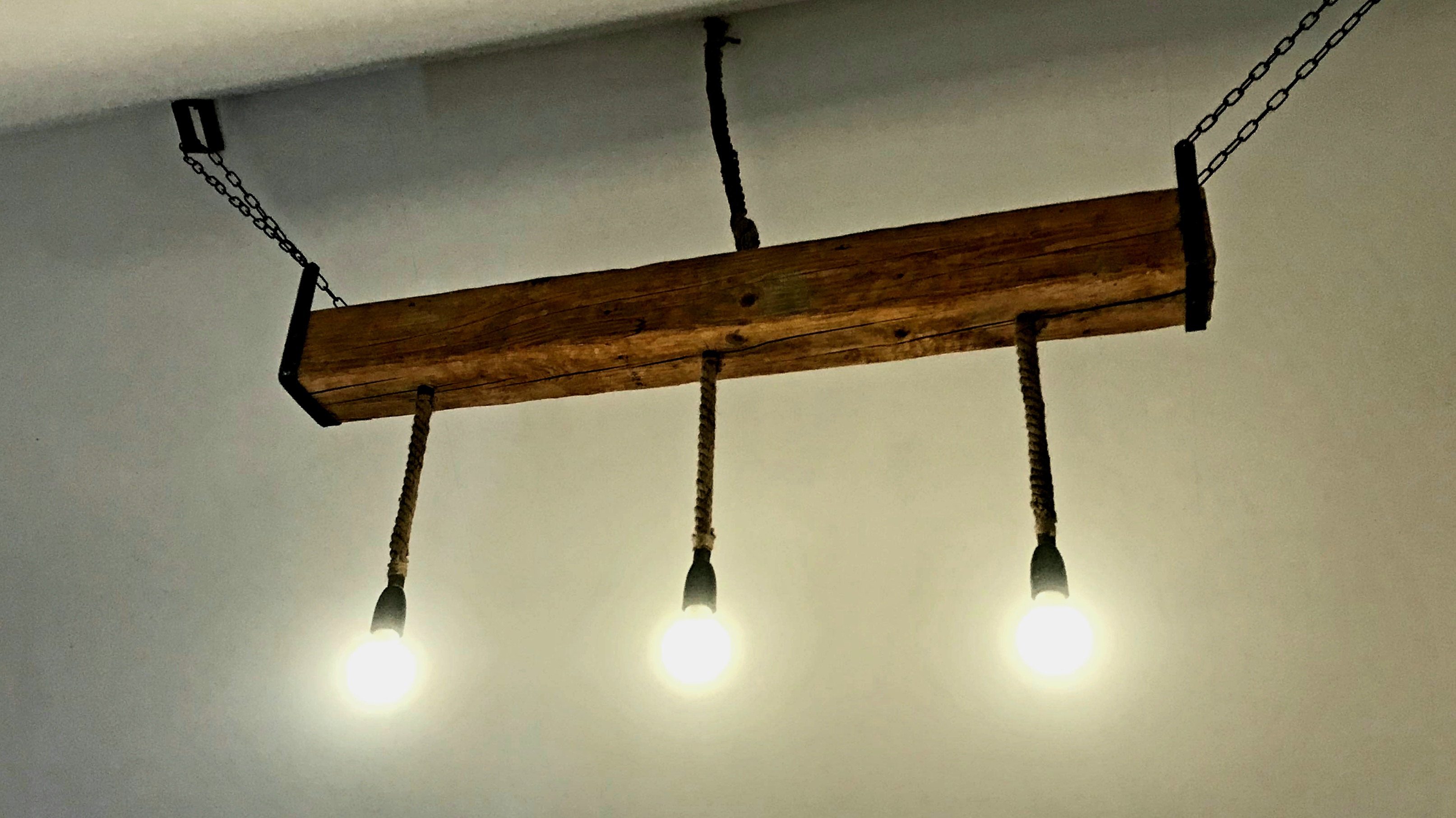 Handmade wooden beam light with Edison bulbs on chains at Magic Garden